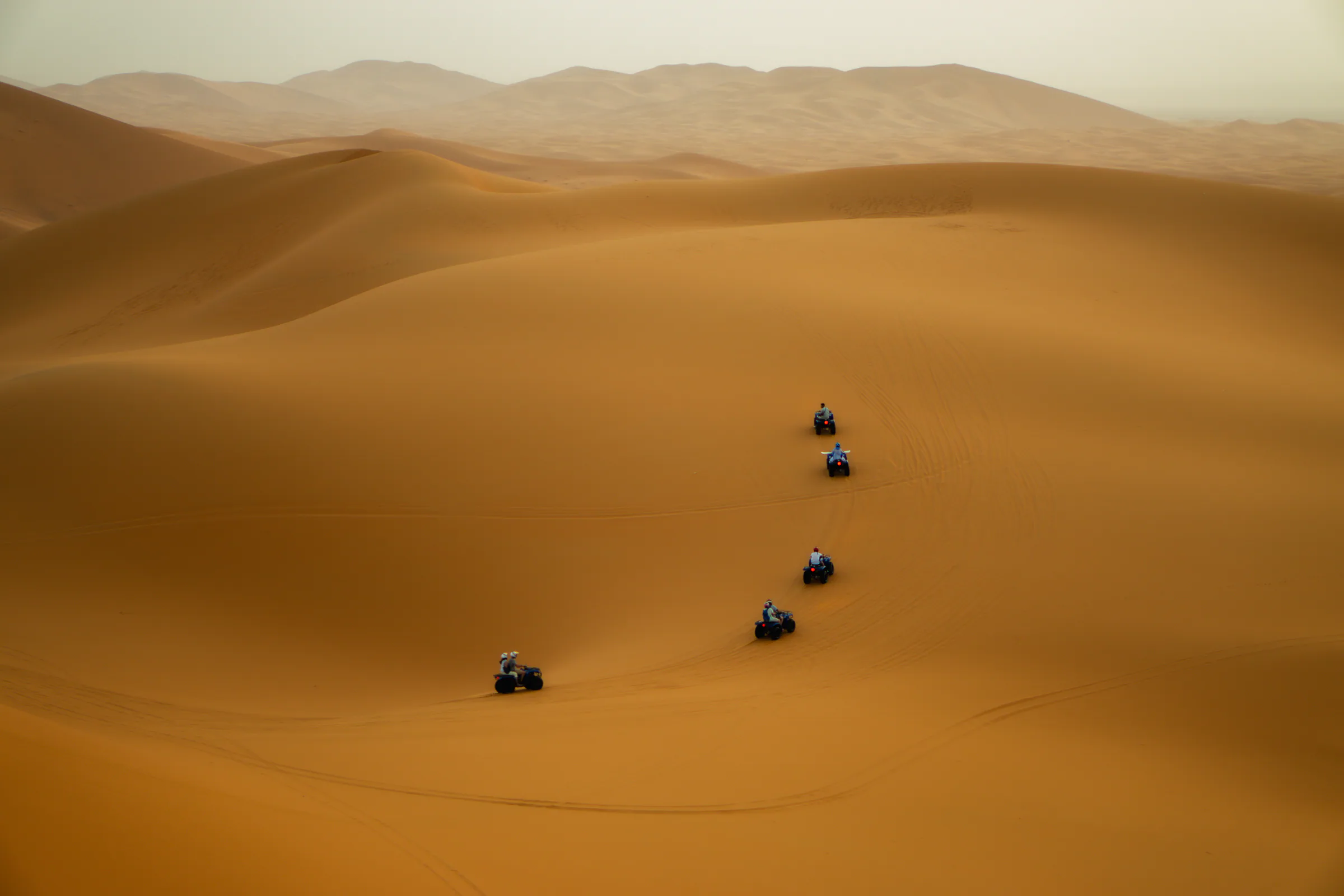 Four-wheel-drive vehicle travelling across Sahara dunes
