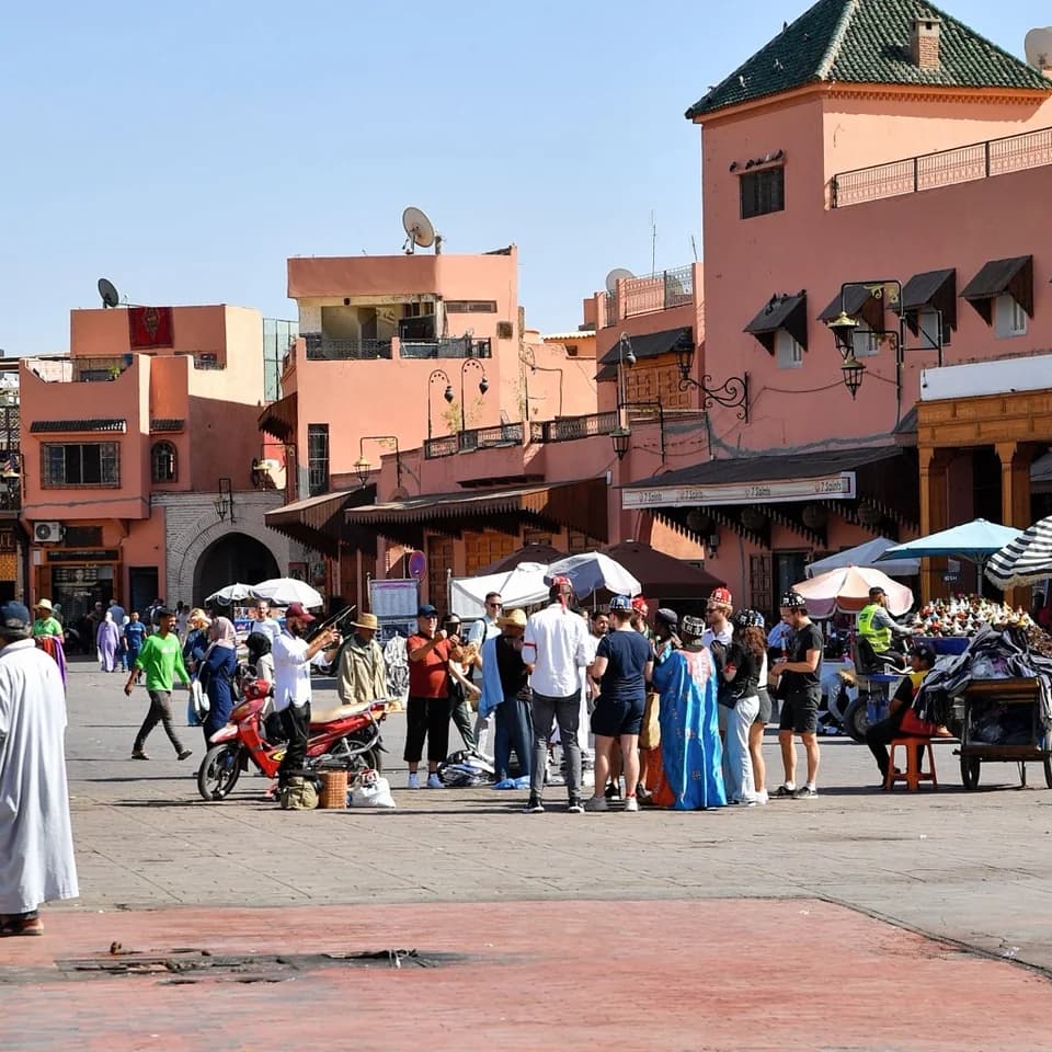 People and market stalls beside the terracotta buildings of Jemaa el-Fnaa