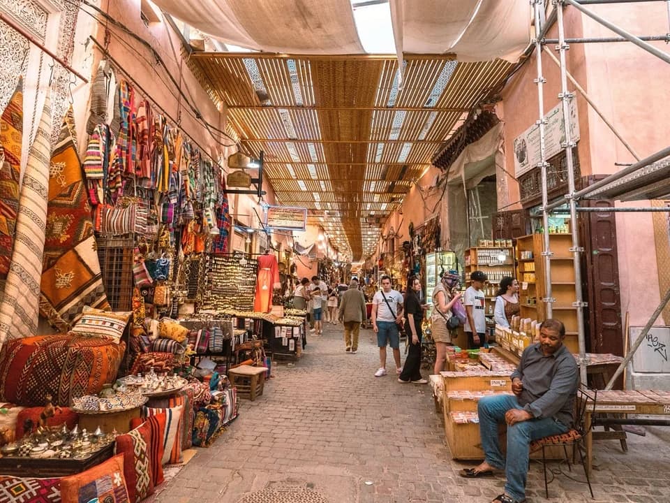 Craft and textile stalls along a covered Marrakech market lane