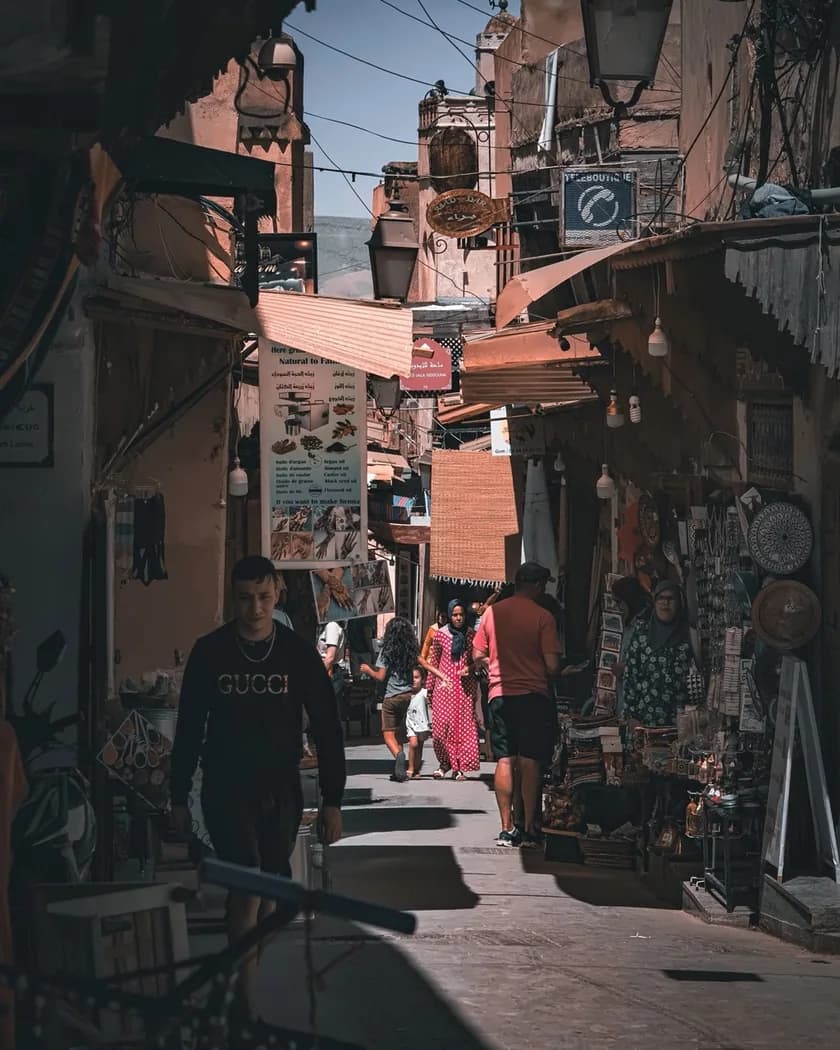 Pedestrians in a narrow Marrakech Medina street lined with shops