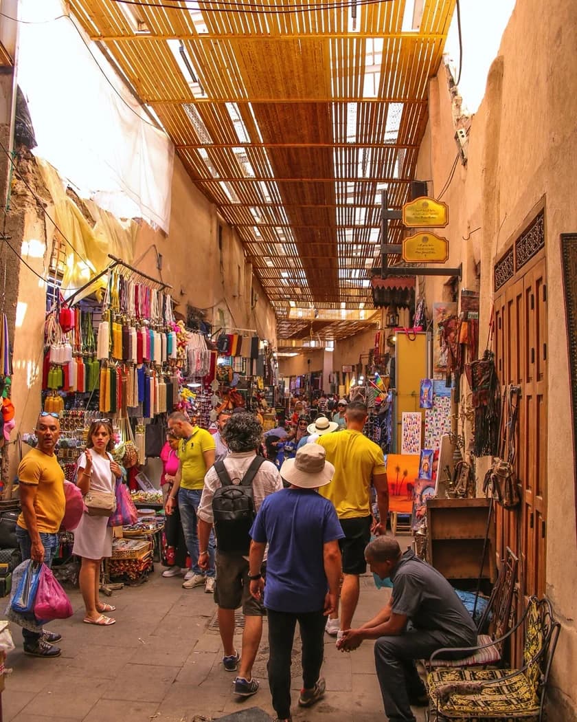 Visitors beneath the slatted roof of a busy Marrakech souk